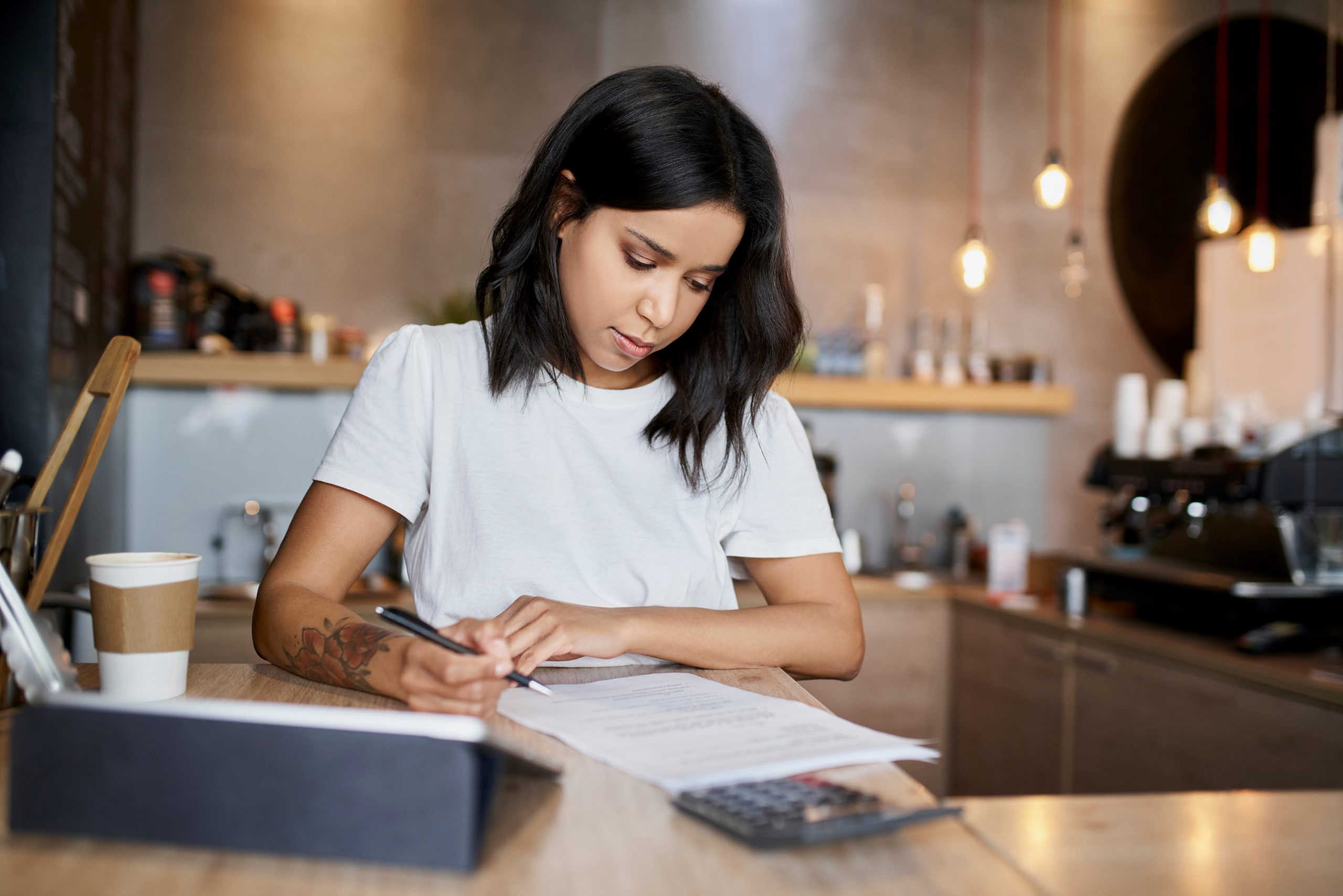 como definir o preço de venda? mulher com calculadora, papel e caneta.