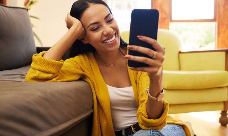 mulher morena de casaco amarelo sorrindo ao olhar para a tela de um smartphone - mudanças no pix