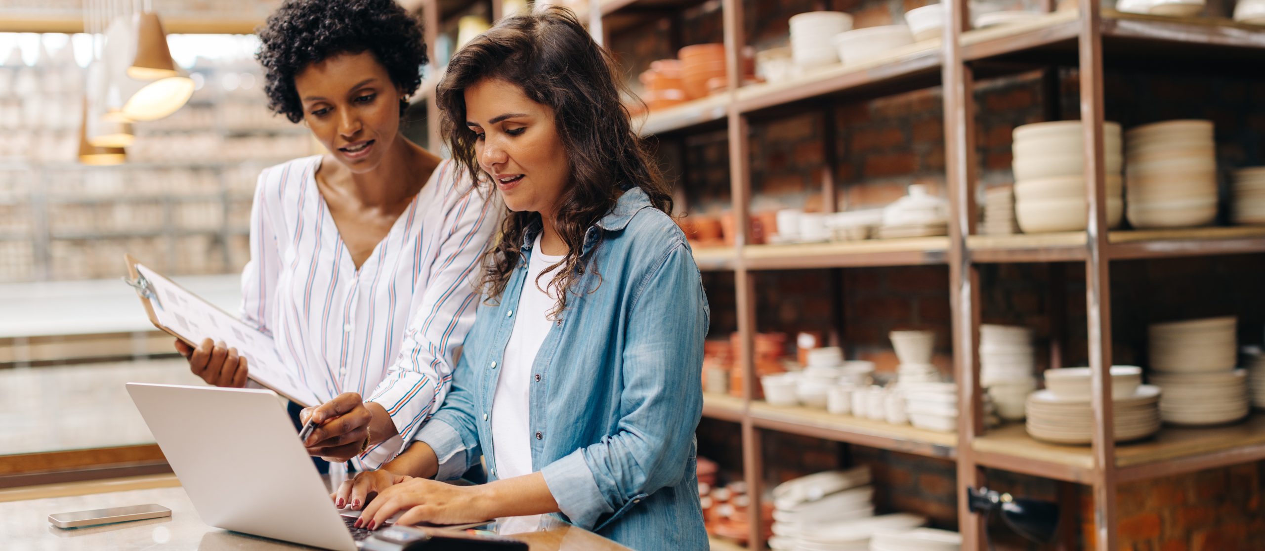 duas mulheres em loja de louças com planilhas e notebook - como precificar