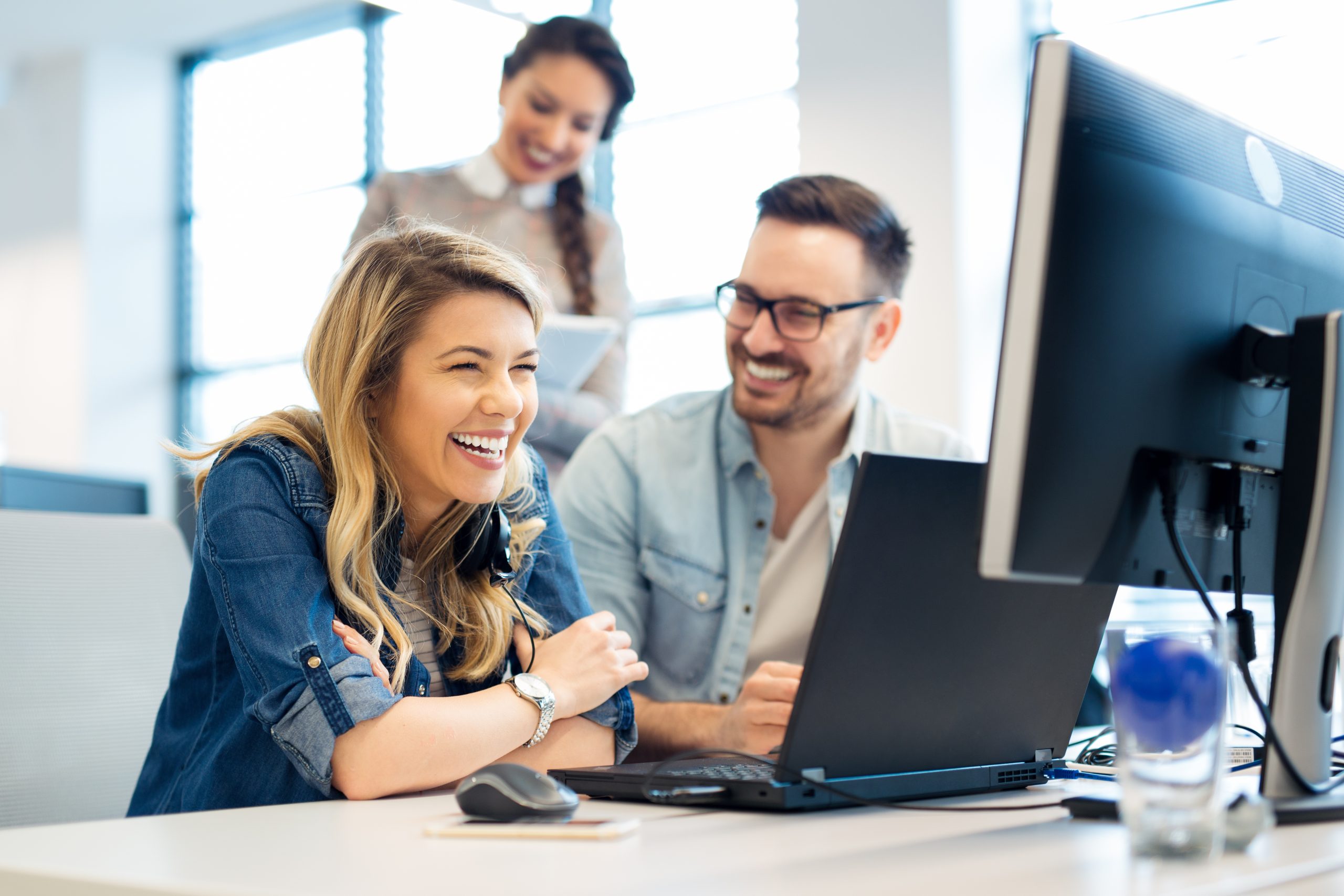 pessoas sorrindo em frente ao computador no trabalho - oportunidades de negócio