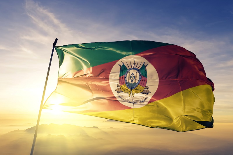 decretos da calamidade no RS - bandeira do Rio Grande do Sul com a luz solar ao fundo.