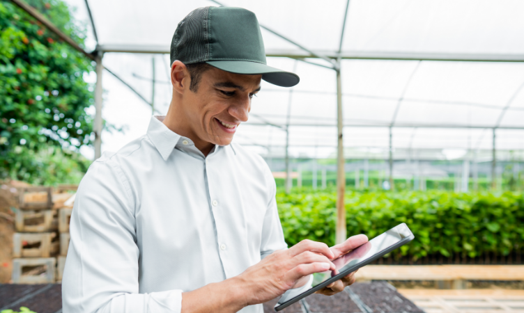 Imagem destaque do blog post do Sebrae RS sobre a retomada do agro gaúcho. A imagem contém um homem segurando um tablet. Ele está dentro de uma estufa de plantas.