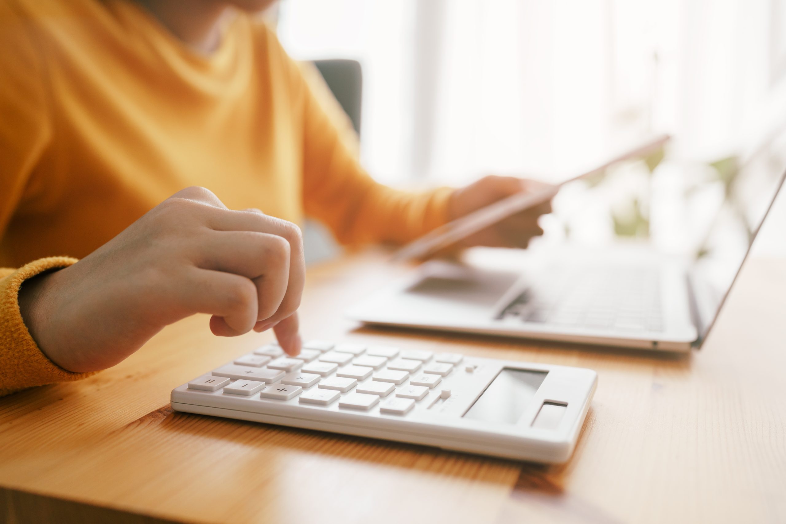 imagem de pessoa fazendo cálculos em uma mesa com notebook e calculdora - CNPJ em dia