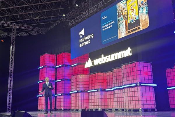 web summit rio 2025 - imagem do telão do evento, nas cores rosa e vermelho, com palestrante em frente a sua apresentação