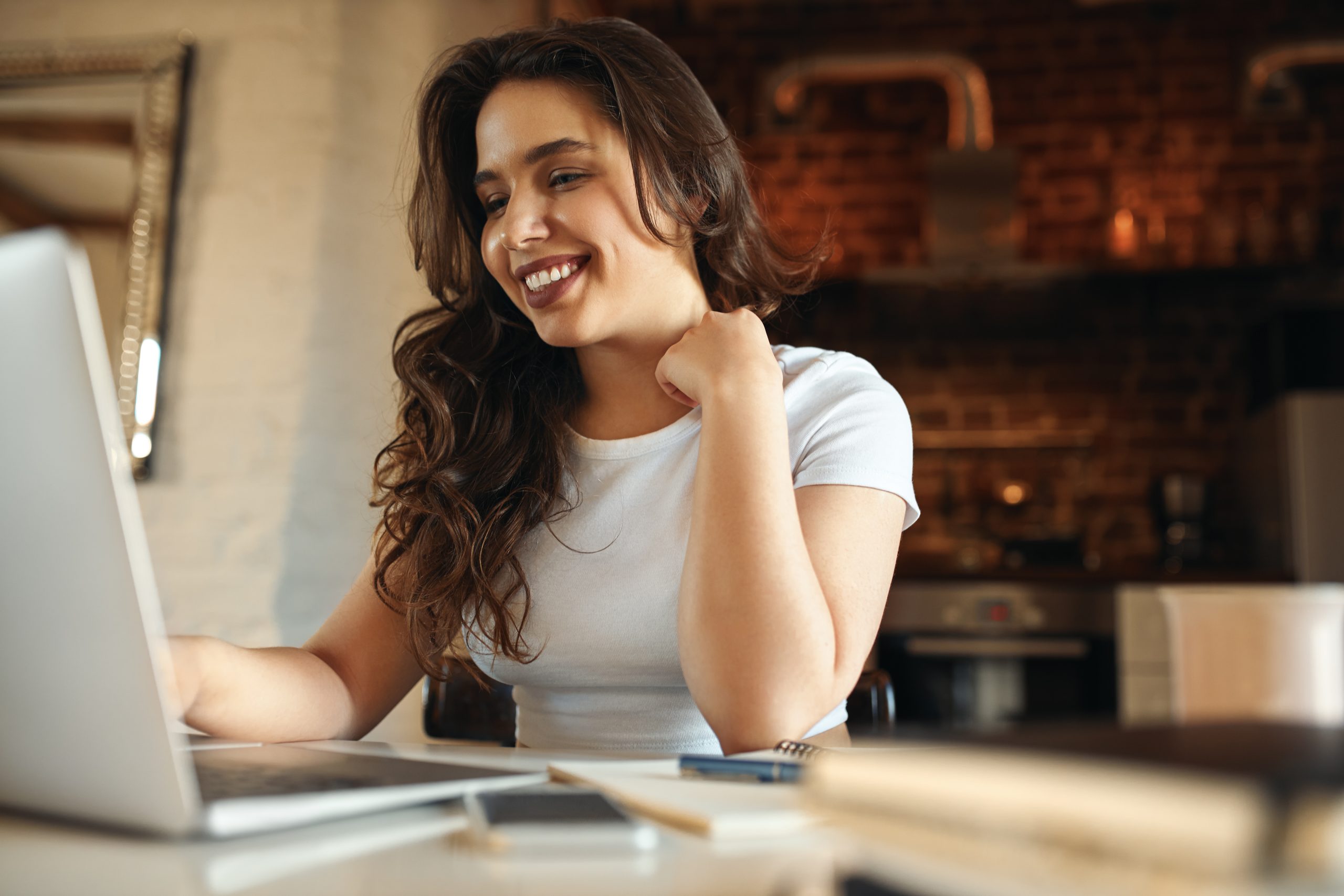blogpost gestão para o MEI - mulher jovem, sentada em frente à uma mesa, sorrindo e olhando para o notebook,