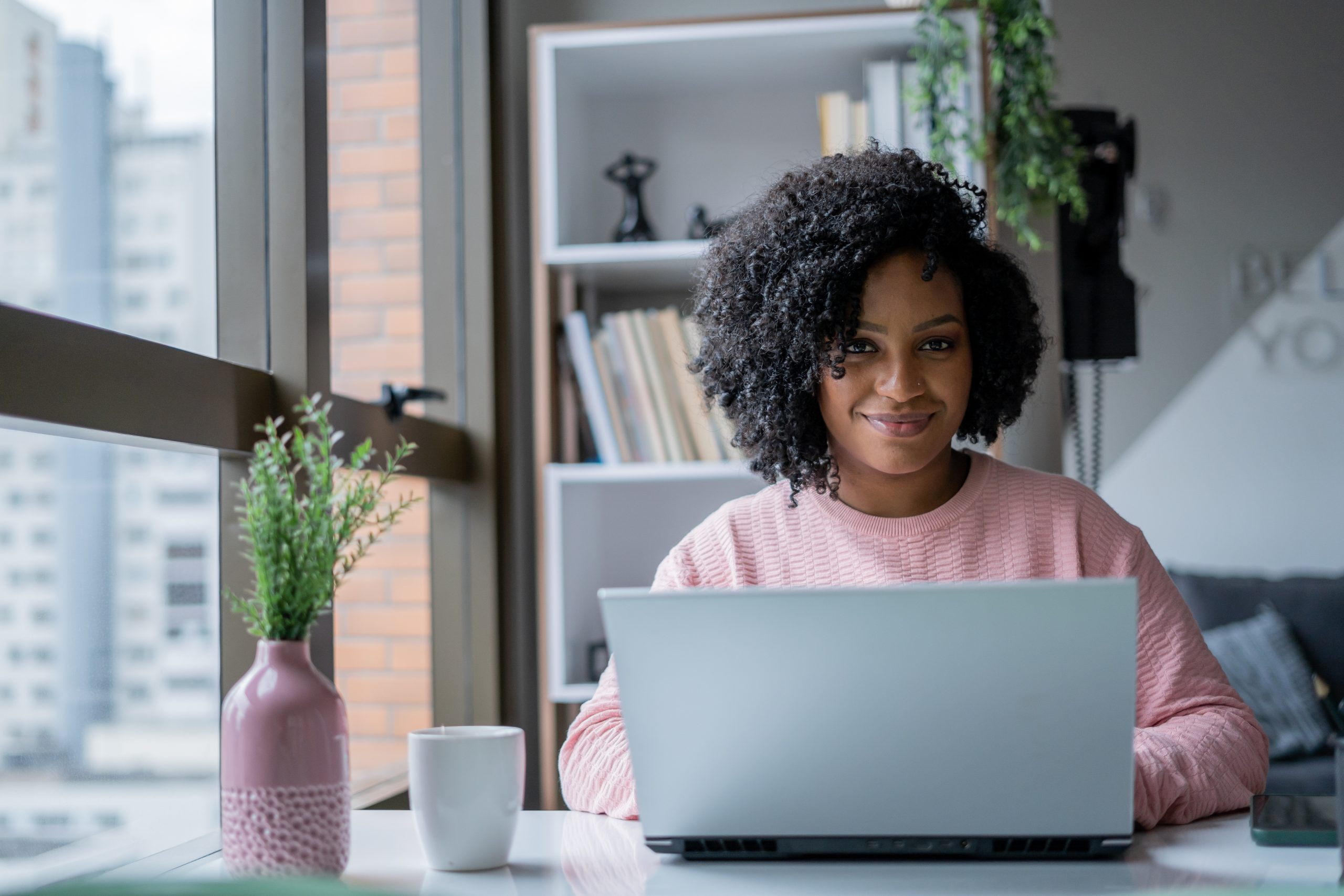 Imagem blogpost Criar site ou app com IA. Mulher em seu escritório sentada em frente ao computador. 