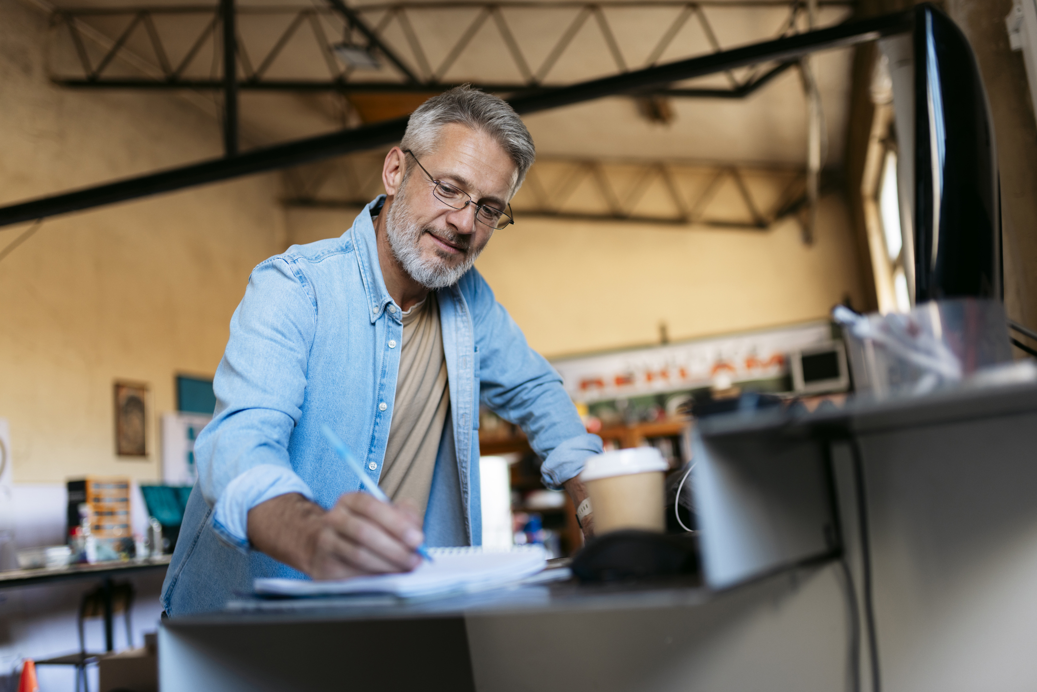 Imagem blog Contratar funcionário em 2026. Homem em seu ambiente de trabalho fazendo anotações. 