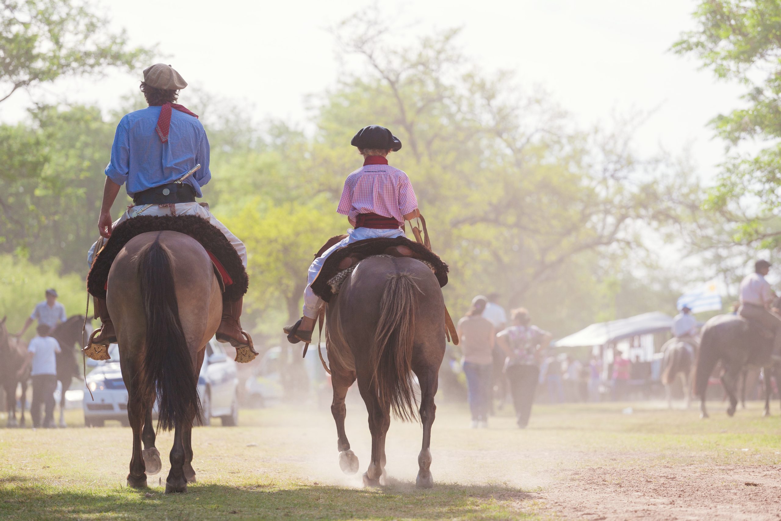 blogpost oportunidades de negócios na Semana Farroupilha - imagem de homem e criança de costas, pilchados (roupa típica gaucha), andando a cavalo.